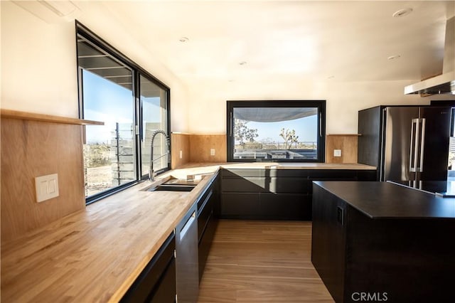 3977 Sage Ave, Yucca Valley, CA 92284 - kitchen with stainless steel appliances, a sink, wood finished floors, wall chimney exhaust hood, and dark cabinets