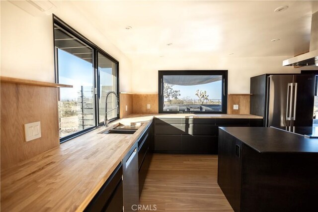 3977 Sage Ave, Yucca Valley, CA 92284 - kitchen featuring appliances with stainless steel finishes, wood finished floors, wall chimney range hood, and dark cabinets