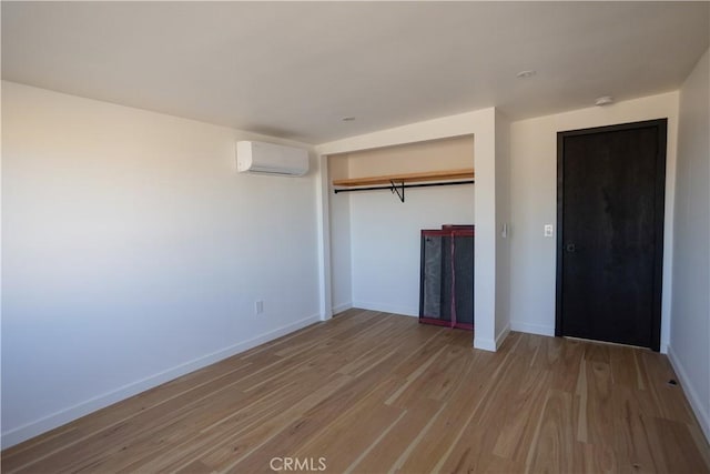 3977 Sage Ave, Yucca Valley, CA 92284 - unfurnished bedroom featuring a wall mounted AC, wood finished floors, baseboards, and a closet