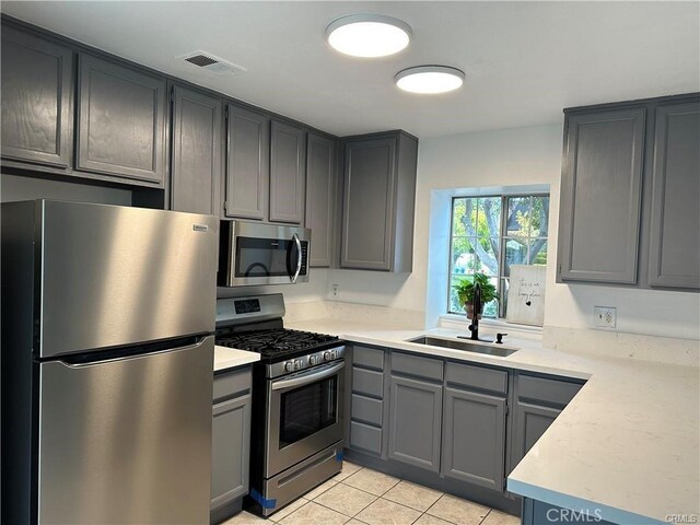 3030 Twincreek Ave, Palmdale, CA 93551 - kitchen featuring stainless steel appliances, a sink, gray cabinets, light tile patterned floors, and light countertops