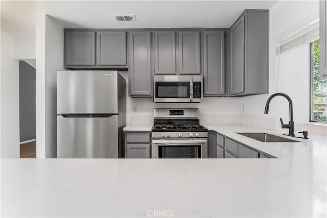 3030 Twincreek Ave, Palmdale, CA 93551 - kitchen with stainless steel appliances, gray cabinetry, plenty of natural light, and light stone countertops