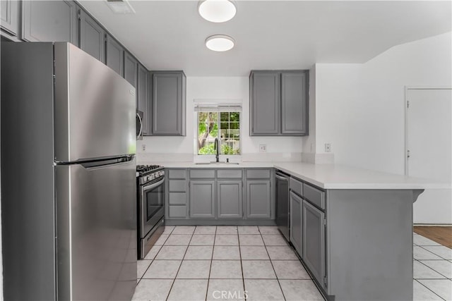 3030 Twincreek Ave, Palmdale, CA 93551 - kitchen with appliances with stainless steel finishes, a peninsula, gray cabinetry, light tile patterned flooring, and light countertops