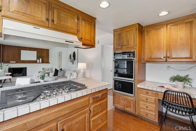 17442 Parker Dr, Tustin, CA 92780 - kitchen with tile counters, stainless steel gas cooktop, light wood-style flooring, recessed lighting, and open floor plan
