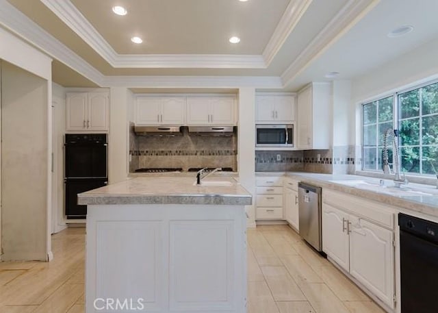 18853 Beechtree Ln, Porter Ranch, CA 91326 - kitchen with black appliances, a kitchen island with sink, crown molding, a raised ceiling, and tasteful backsplash