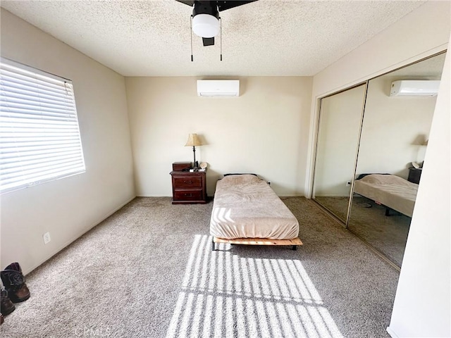 5374 Morongo Rd Unit 29, Palms, CA 92277 - carpeted bedroom featuring a wall mounted air conditioner, a textured ceiling, a closet, and ceiling fan