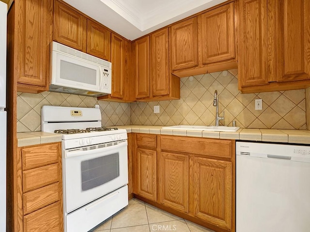 16879 Bluewater Ln Unit 25, Huntington Beach, CA 92649 - kitchen with white appliances, a sink, backsplash, tile counters, and brown cabinets