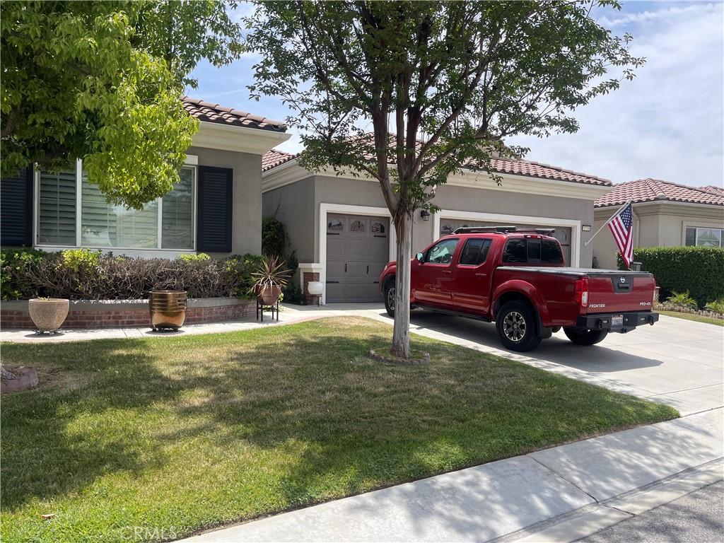 1734 Las Colinas Rd, Beaumont, CA 92223 - view of front of home with driveway, an attached garage, a front yard, stucco siding, and a tiled roof