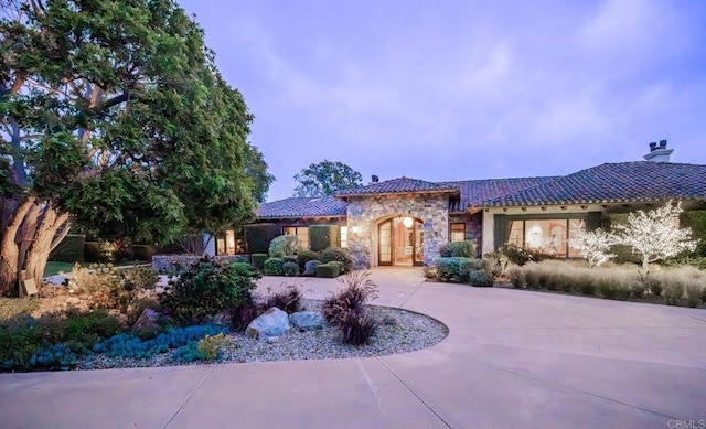 4843 La Jacaranda, Rancho Santa Fe, CA 92067 - mediterranean / spanish-style house featuring stone siding, a tiled roof, a chimney, and curved driveway