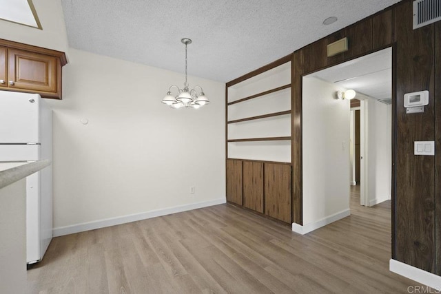 5938 Rancho Mission Rd Unit 133, San Diego, CA 92108 - unfurnished dining area featuring light wood-style flooring, a chandelier, a textured ceiling, and baseboards