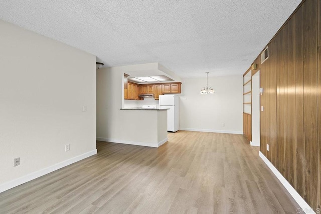 5938 Rancho Mission Rd Unit 133, San Diego, CA 92108 - unfurnished living room with a chandelier, light wood-type flooring, wood walls, a textured ceiling, and baseboards