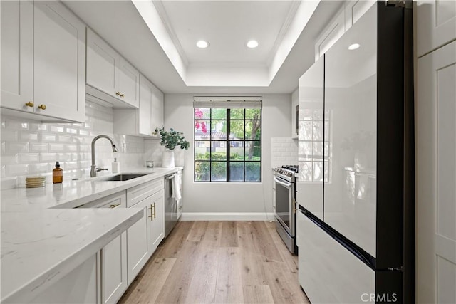 1202 Monte Sereno Dr, Thousand Oaks, CA 91360 - kitchen with stainless steel appliances, a sink, white cabinetry, a raised ceiling, and light wood-type flooring