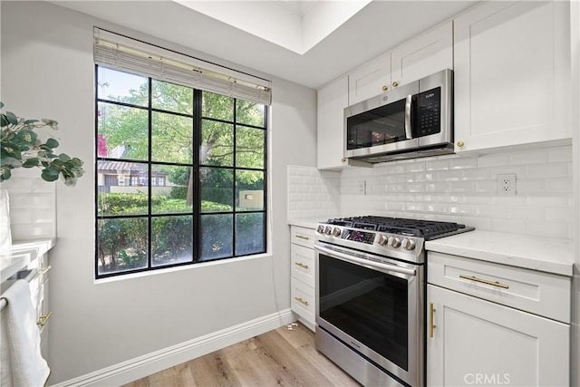 1202 Monte Sereno Dr, Thousand Oaks, CA 91360 - kitchen featuring appliances with stainless steel finishes, light wood-style floors, white cabinetry, tasteful backsplash, and baseboards
