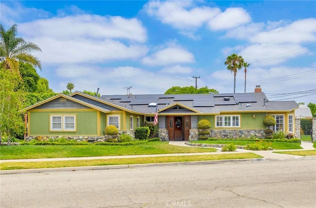 12071 Reva Dr, Garden Grove, CA 92840 - ranch-style house with stone siding, a front lawn, roof mounted solar panels, and a chimney