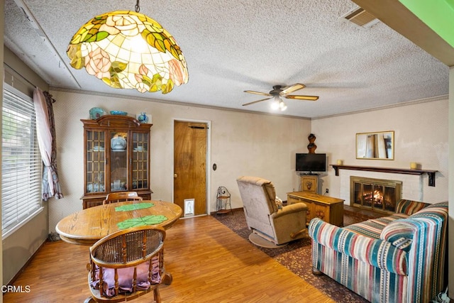 4320 Hamilton Ave, Oxnard, CA 93033 - living room featuring wood finished floors, a textured ceiling, a ceiling fan, crown molding, and a brick fireplace