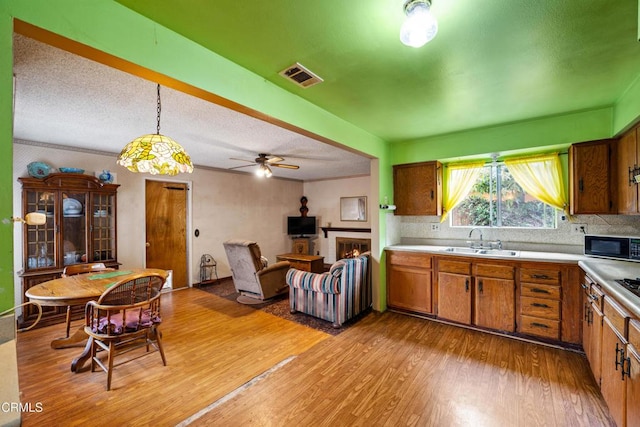 4320 Hamilton Ave, Oxnard, CA 93033 - kitchen featuring a sink, black microwave, brown cabinetry, light wood finished floors, and light countertops