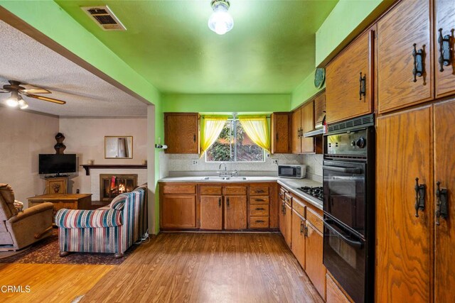 4320 Hamilton Ave, Oxnard, CA 93033 - kitchen featuring black appliances, brown cabinets, light countertops, light wood finished floors, and decorative backsplash