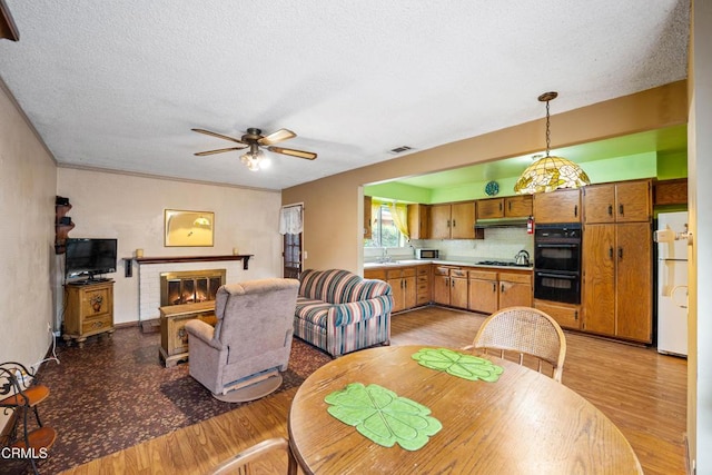 4320 Hamilton Ave, Oxnard, CA 93033 - dining space with light wood-type flooring, a ceiling fan, a textured ceiling, and a fireplace