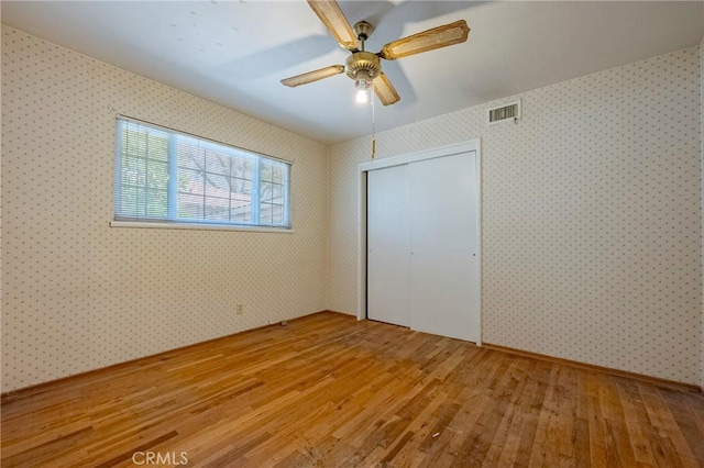 1640 Shirley St, Merced, CA 95341 - unfurnished bedroom with light wood-style flooring, wallpapered walls, a closet, and a ceiling fan
