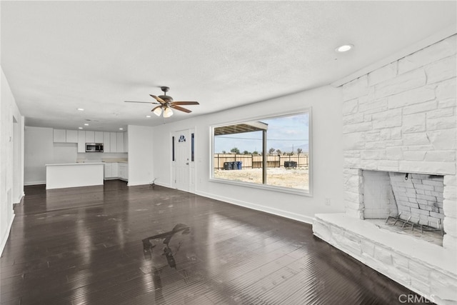 18531 E Palmdale Blvd, Palmdale, CA 93591 - unfurnished living room with a stone fireplace, ceiling fan, baseboards, dark wood-style flooring, and recessed lighting