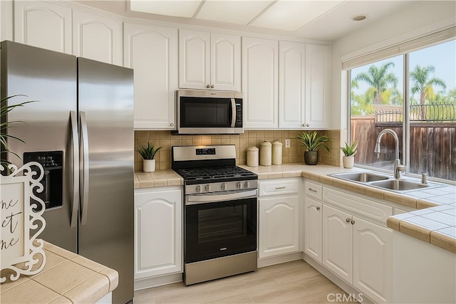 24982 La Pantera, Laguna Niguel, CA 92677 - kitchen featuring stainless steel appliances, tile countertops, white cabinets, and tasteful backsplash