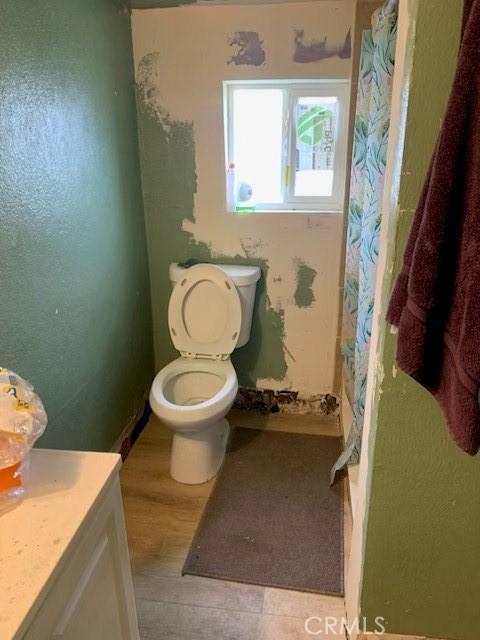 12933 Main St, Waterford, CA 95386 - full bath with toilet, vanity, wood finished floors, and a shower with shower curtain