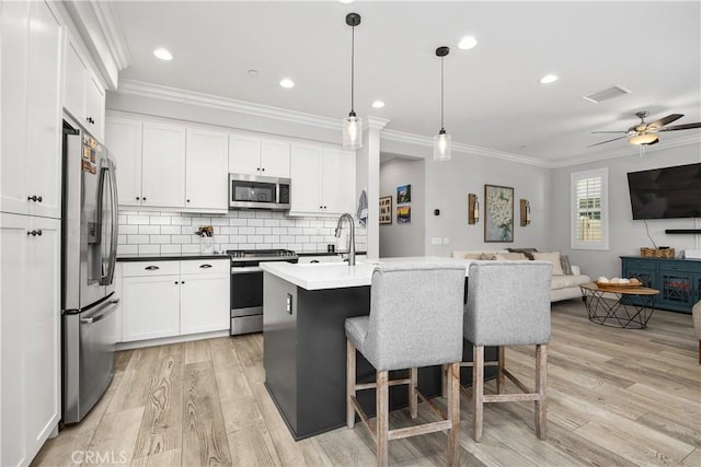45437 Calle Cirros, Temecula, CA 92592 - kitchen featuring appliances with stainless steel finishes, open floor plan, crown molding, light wood-style floors, and white cabinets