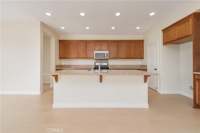 6611 Eucalyptus Ave, Chino, CA 91710 - kitchen with appliances with stainless steel finishes, brown cabinets, recessed lighting, a kitchen bar, and a kitchen island with sink