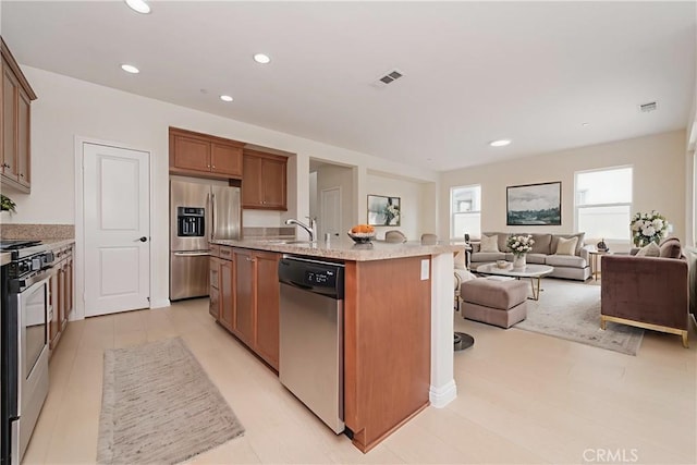 6611 Eucalyptus Ave, Chino, CA 91710 - kitchen with appliances with stainless steel finishes, open floor plan, a center island with sink, brown cabinets, and recessed lighting