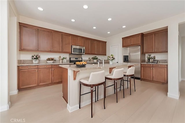 6611 Eucalyptus Ave, Chino, CA 91710 - kitchen with stainless steel appliances, an island with sink, a breakfast bar, recessed lighting, and light stone countertops