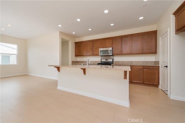 6611 Eucalyptus Ave, Chino, CA 91710 - kitchen with stainless steel microwave, stove, recessed lighting, a kitchen breakfast bar, and brown cabinets