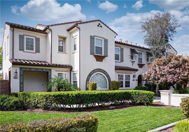 6611 Eucalyptus Ave, Chino, CA 91710 - mediterranean / spanish-style home with a tiled roof, stucco siding, a front yard, and an attached garage