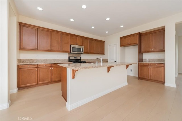 6611 Eucalyptus Ave, Chino, CA 91710 - kitchen with stainless steel appliances, brown cabinets, a breakfast bar area, light stone counters, and recessed lighting