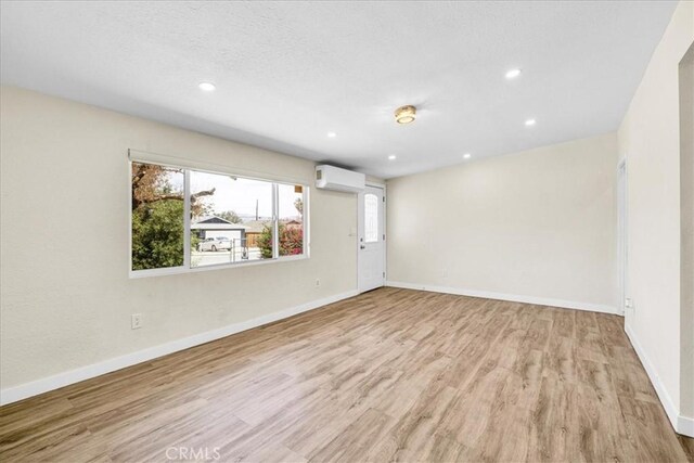 6064 Cahuilla Ave Unit 29, Palms, CA 92277 - unfurnished room featuring a wall mounted AC, wood finished floors, baseboards, and recessed lighting