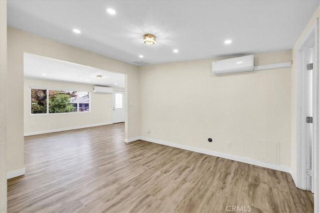 6064 Cahuilla Ave Unit 29, Palms, CA 92277 - unfurnished living room with an AC wall unit, light wood-type flooring, a wall mounted AC, recessed lighting, and baseboards