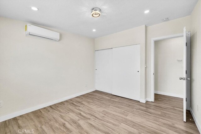 6064 Cahuilla Ave Unit 29, Palms, CA 92277 - unfurnished bedroom featuring light wood-style floors, an AC wall unit, a closet, baseboards, and recessed lighting