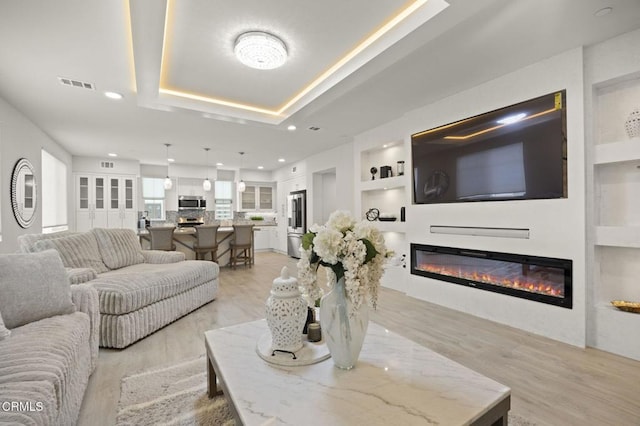 2850 Wagon Wheel Rd Unit 302, Oxnard, CA 93036 - living room with a glass covered fireplace, light wood-style flooring, built in features, a tray ceiling, and recessed lighting