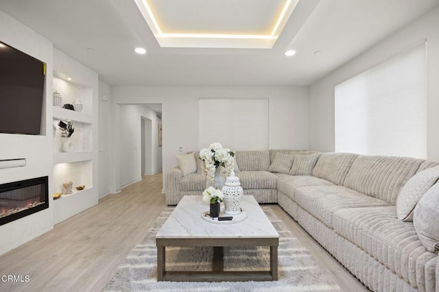 2850 Wagon Wheel Rd Unit 302, Oxnard, CA 93036 - living room featuring light wood-style flooring, recessed lighting, a glass covered fireplace, and a tray ceiling