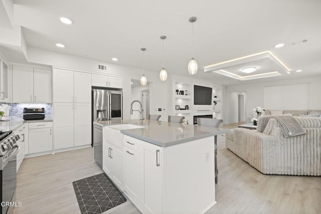 2850 Wagon Wheel Rd Unit 302, Oxnard, CA 93036 - kitchen featuring open floor plan, a sink, appliances with stainless steel finishes, light wood-style floors, and white cabinets