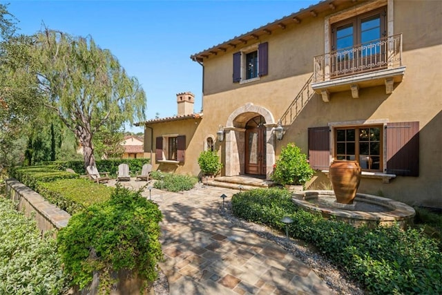 97 Canyon Crk, Irvine, CA 92603 - mediterranean / spanish-style house featuring a balcony, stucco siding, a chimney, and a patio