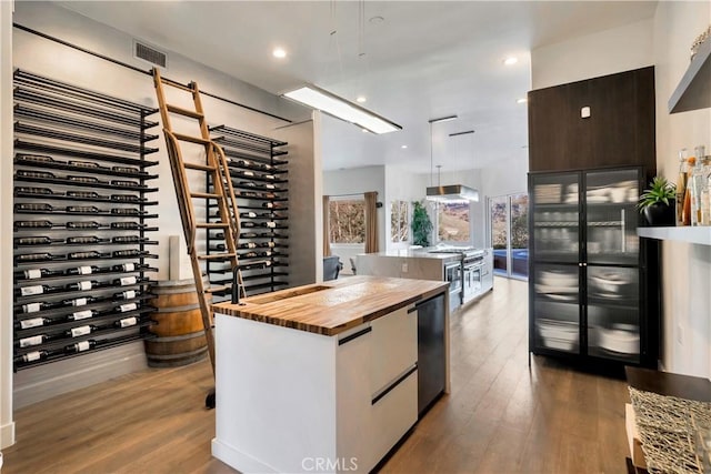 30402 Marbella, San Juan Capistrano, CA 92675 - kitchen featuring wooden counters, a center island with sink, wood finished floors, hanging light fixtures, and recessed lighting