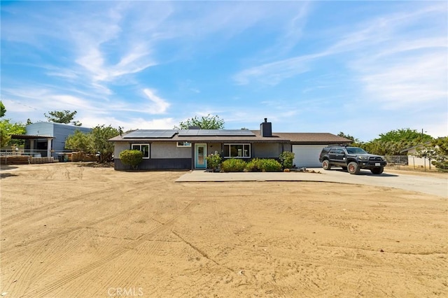 14650 Harding St, Hesperia, CA 92345 - view of front facade featuring driveway, roof mounted solar panels, a garage, and a chimney
