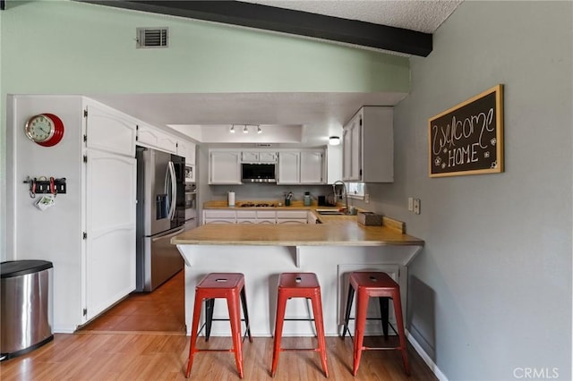 14650 Harding St, Hesperia, CA 92345 - kitchen featuring stainless steel appliances, a peninsula, a sink, beamed ceiling, and light countertops