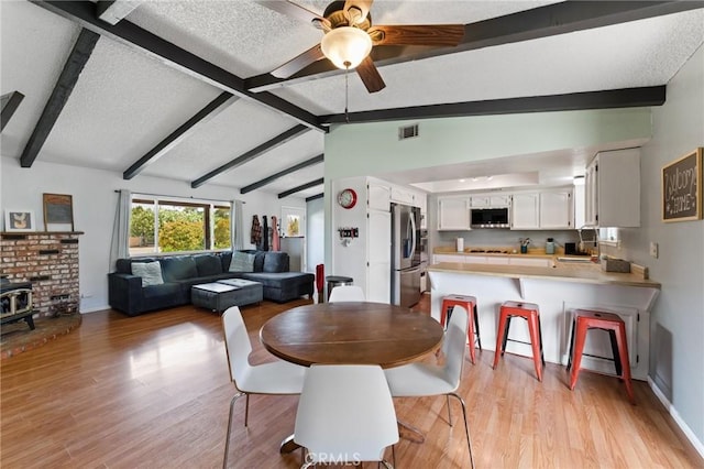 14650 Harding St, Hesperia, CA 92345 - dining area with light wood-style flooring, a wood stove, a ceiling fan, and a textured ceiling