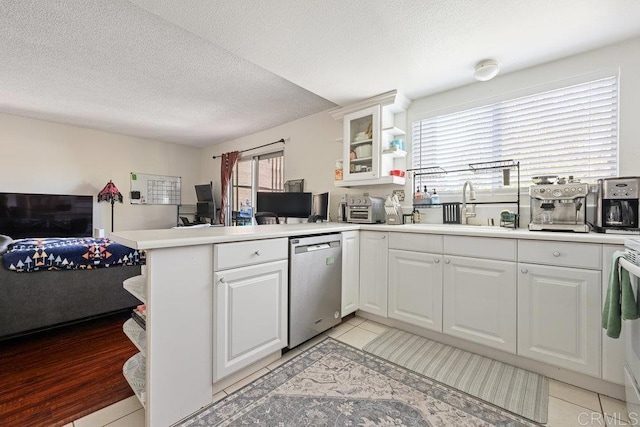 155 Rosebay Dr Unit 42, Encinitas, CA 92024 - kitchen with stainless steel dishwasher, a sink, a peninsula, glass insert cabinets, and white cabinetry