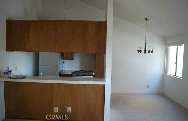 6188 Agee St Unit 230, San Diego, CA 92122 - kitchen with freestanding refrigerator, brown cabinets, a chandelier, lofted ceiling, and stainless steel gas range