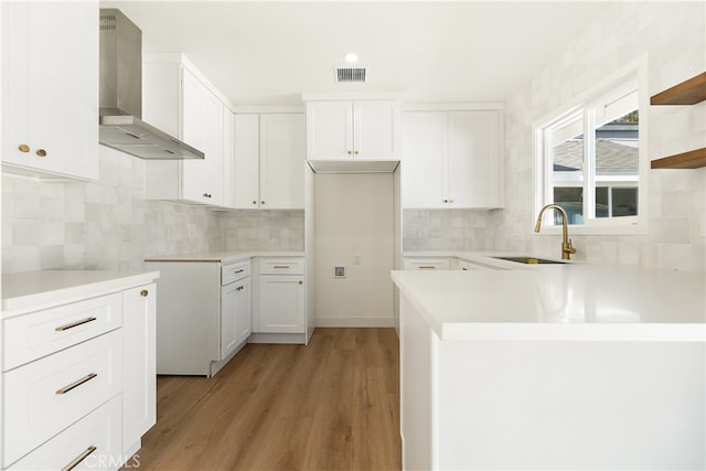 1027 E 10th St, Long Beach, CA 90813 - kitchen with wall chimney range hood, a sink, light wood-style flooring, tasteful backsplash, and white cabinets