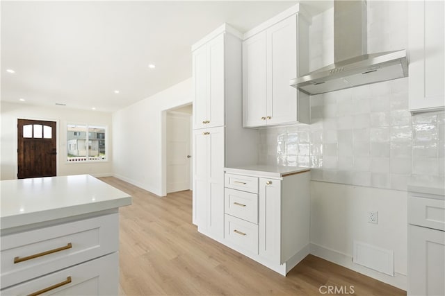 1027 E 10th St, Long Beach, CA 90813 - kitchen with wall chimney range hood, light countertops, tasteful backsplash, light wood-type flooring, and white cabinets