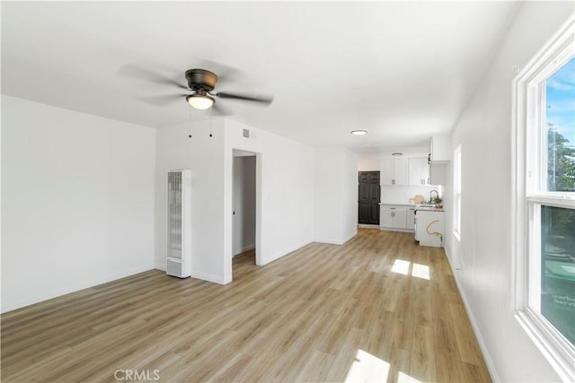 1212 Woodrow Ave, Bakersfield, CA 93308 - unfurnished living room with a heating unit, ceiling fan, light wood-style floors, a sink, and baseboards