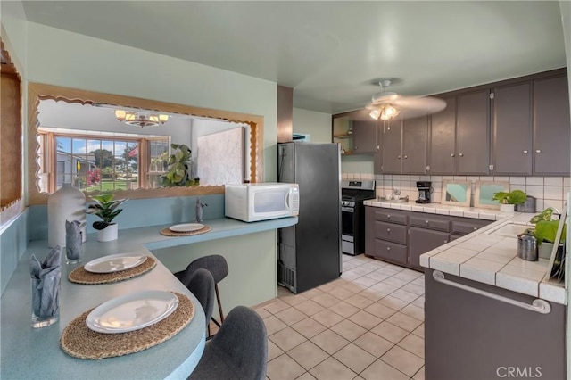 7860 La Fiesta Dr, Buena Park, CA 90620 - kitchen featuring appliances with stainless steel finishes, tile counters, a chandelier, backsplash, and light tile patterned flooring