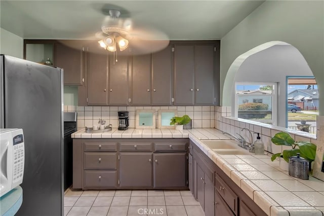 7860 La Fiesta Dr, Buena Park, CA 90620 - kitchen with tile counters, a sink, freestanding refrigerator, and gray cabinetry